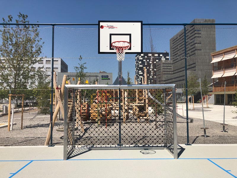 Bolzplatztor Multisport aus Aluminium mit Basketballaufsatz auf rotem Sportplatz