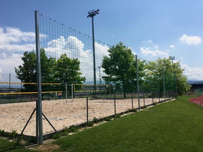 Schutznetz grenzt Beachvolleyballfeld ab, sichert Bälle vor dem Abhang.