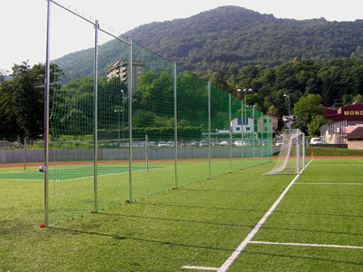 hohe Schutzanlage mit Querstangen auf Sportplatz, Abtrennung Bereiche Fussball und Volleyball